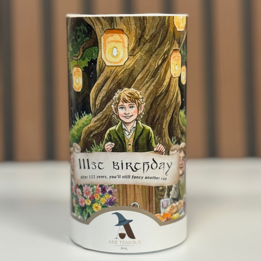 Cylindrical product with a printed design of a hobbit like bilbo and tree, labeled '111st Birthday'.