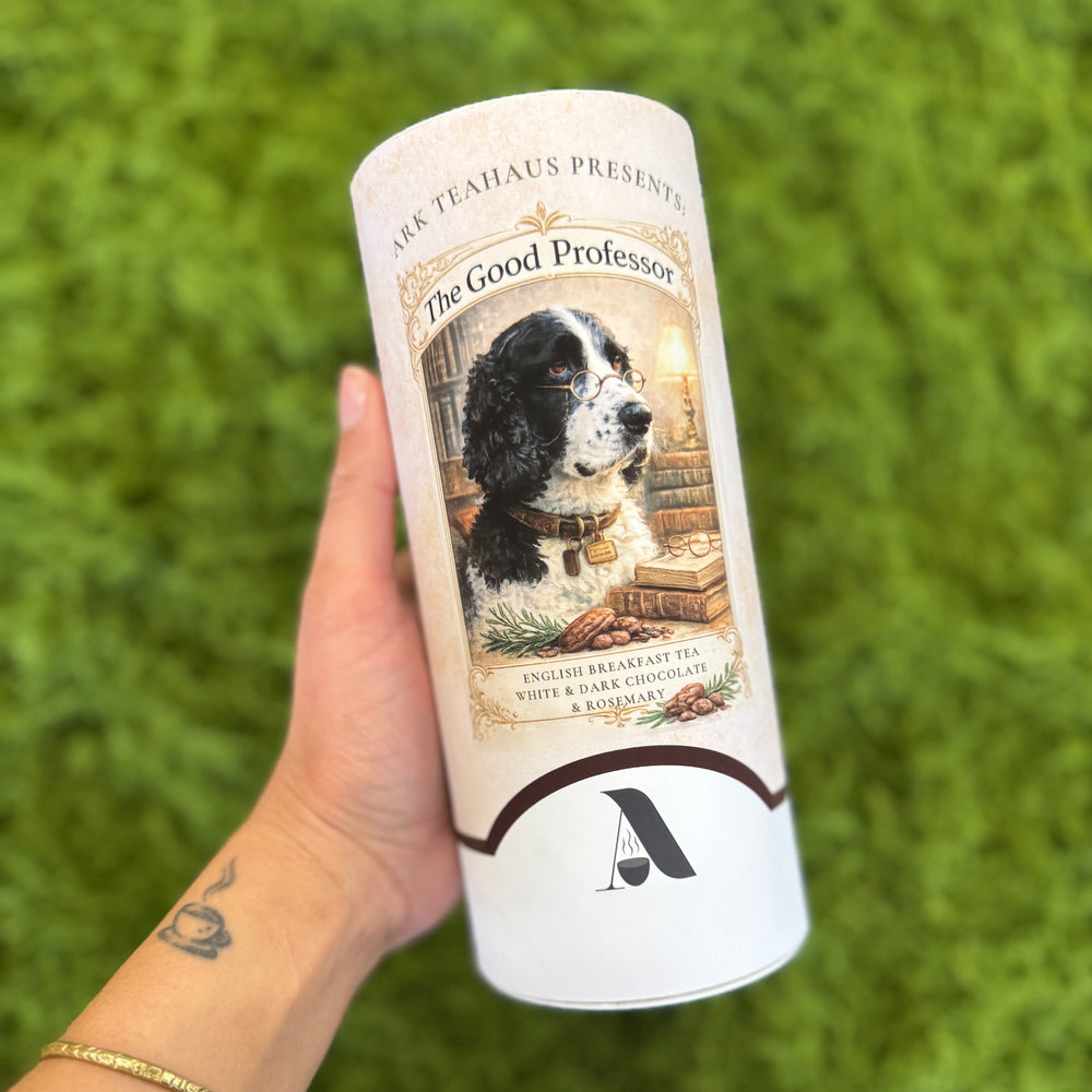 A canister of tea with a black and white english springer spaniel on the front wearing vintage glasses with the text "The Good Professor, English breakfast tea with with and dark chocolate & rosemary"